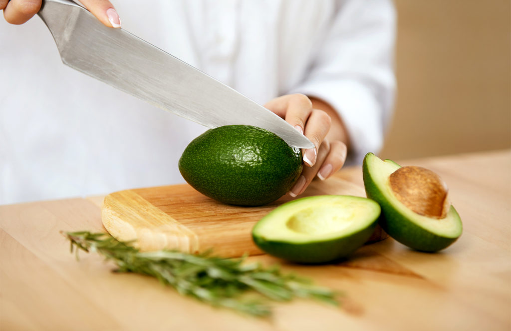 Avocados werden mit einem großem Messer geschnitten