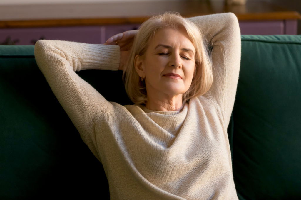 Ältere Frau entspannt mit geschlossenen Augen auf der Couch